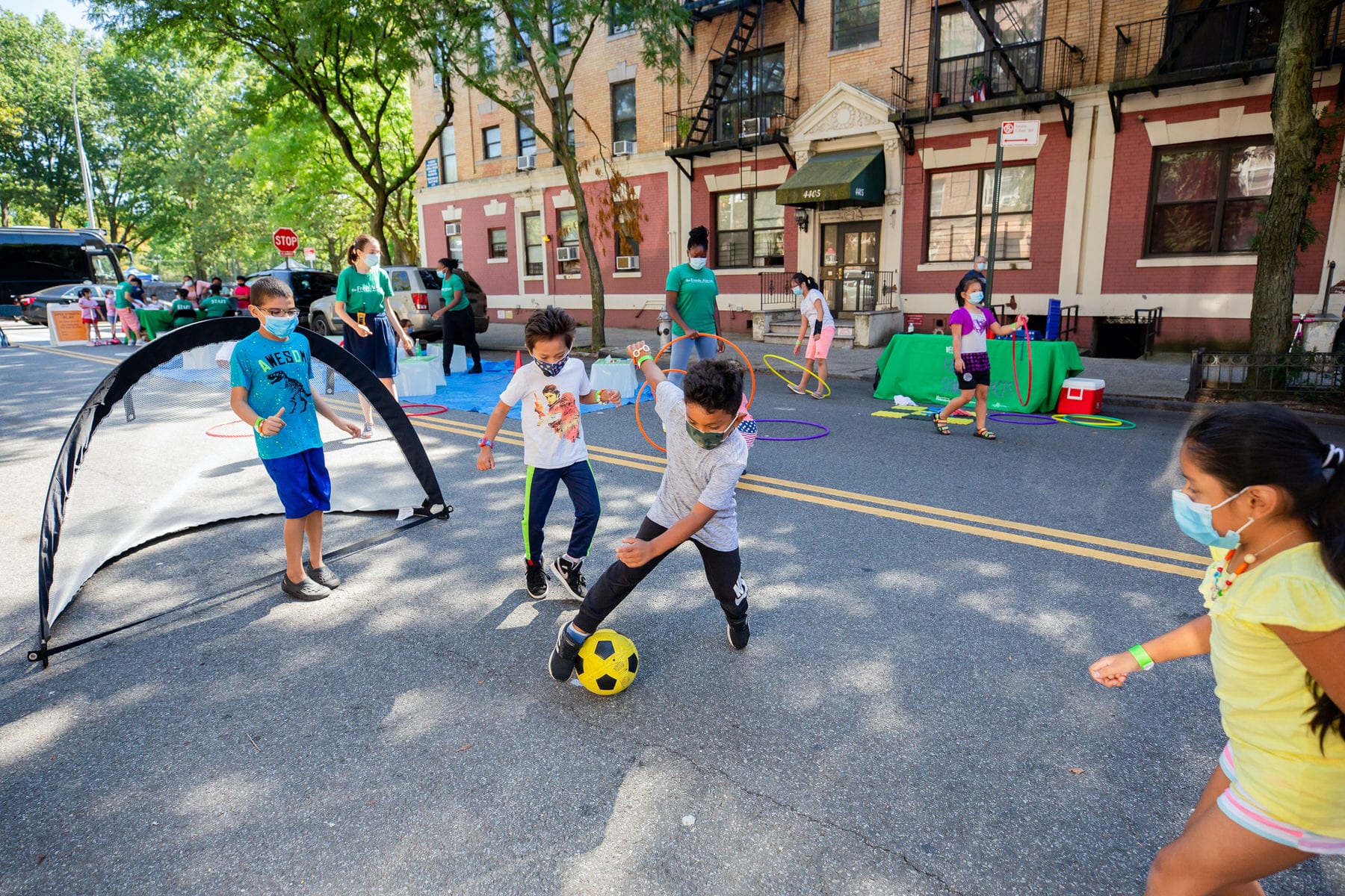 Kids playing soccer on a city street.