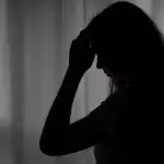 Photo of a depressed teen holding her head.