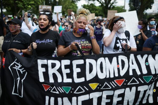 A group women hold a Juneteenth banner during a march.