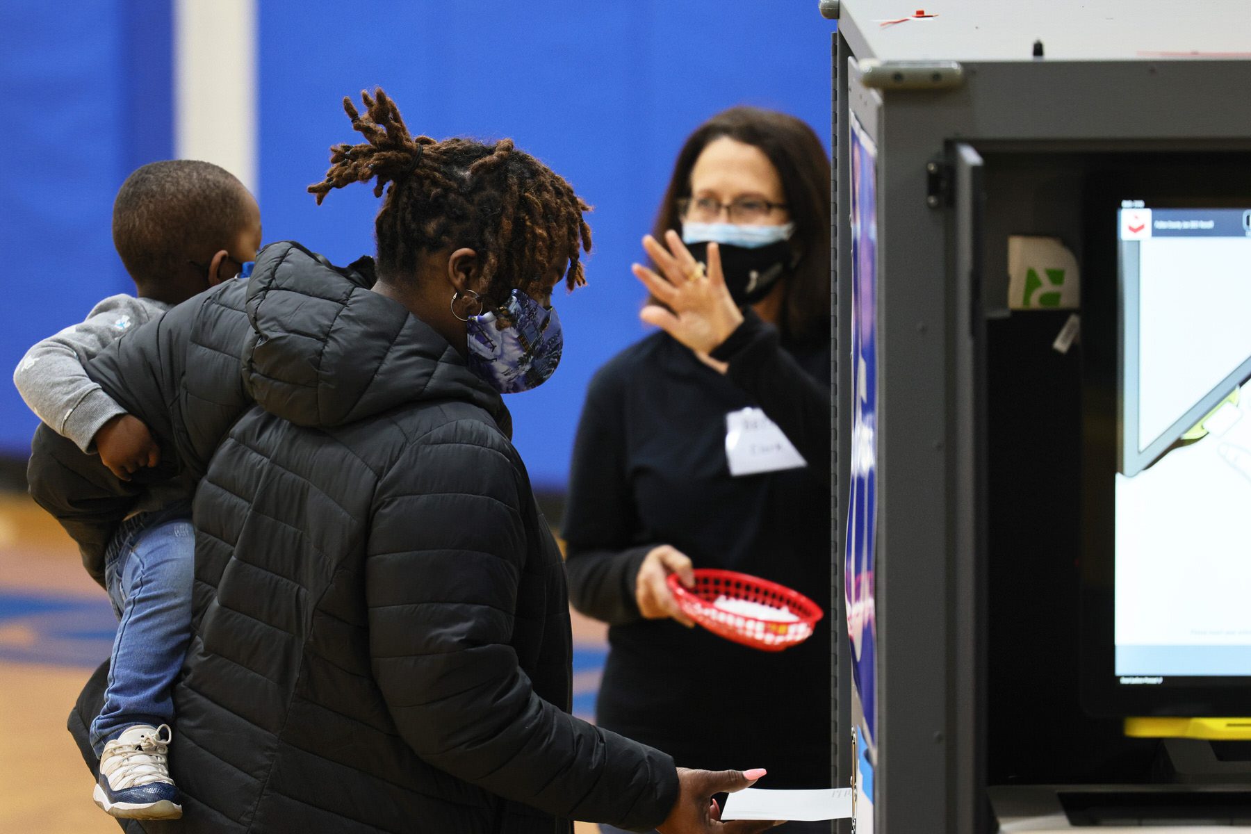 A woman holding a young child casts her vote in the Georgia run-off election at Dunbar Neighborhood Center.