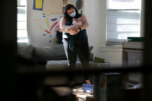 Diana Rastegayeva, who is on maternity leave with her children, with her 3-month-old in their home's living room in Somerville, MA on Feb. 26, 2021. Diana has created a website and recruited hundreds of volunteers who help people get vaccine appointments.