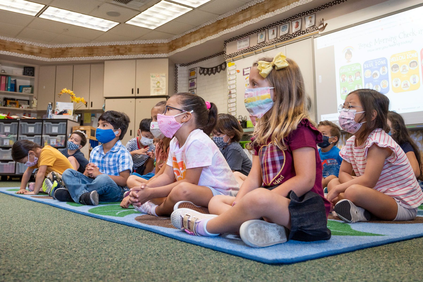 Students listen to their teacher during their first day of kindergarten.