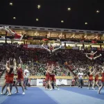 Cheerleaders doing stunts on a competition floor.