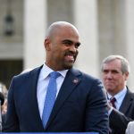 Colin Allred smiling before a microphone.