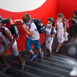 School children wearing masks in a hallway.