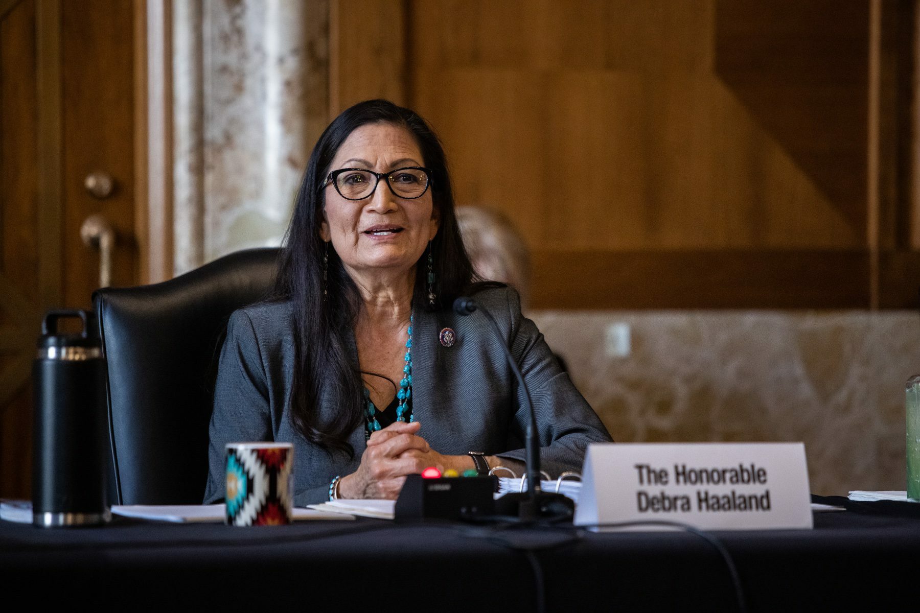 Deb Haaland sitting at a table speaking into a microphone.