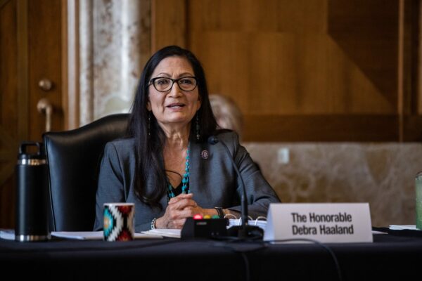 Deb Haaland sitting at a table speaking into a microphone.