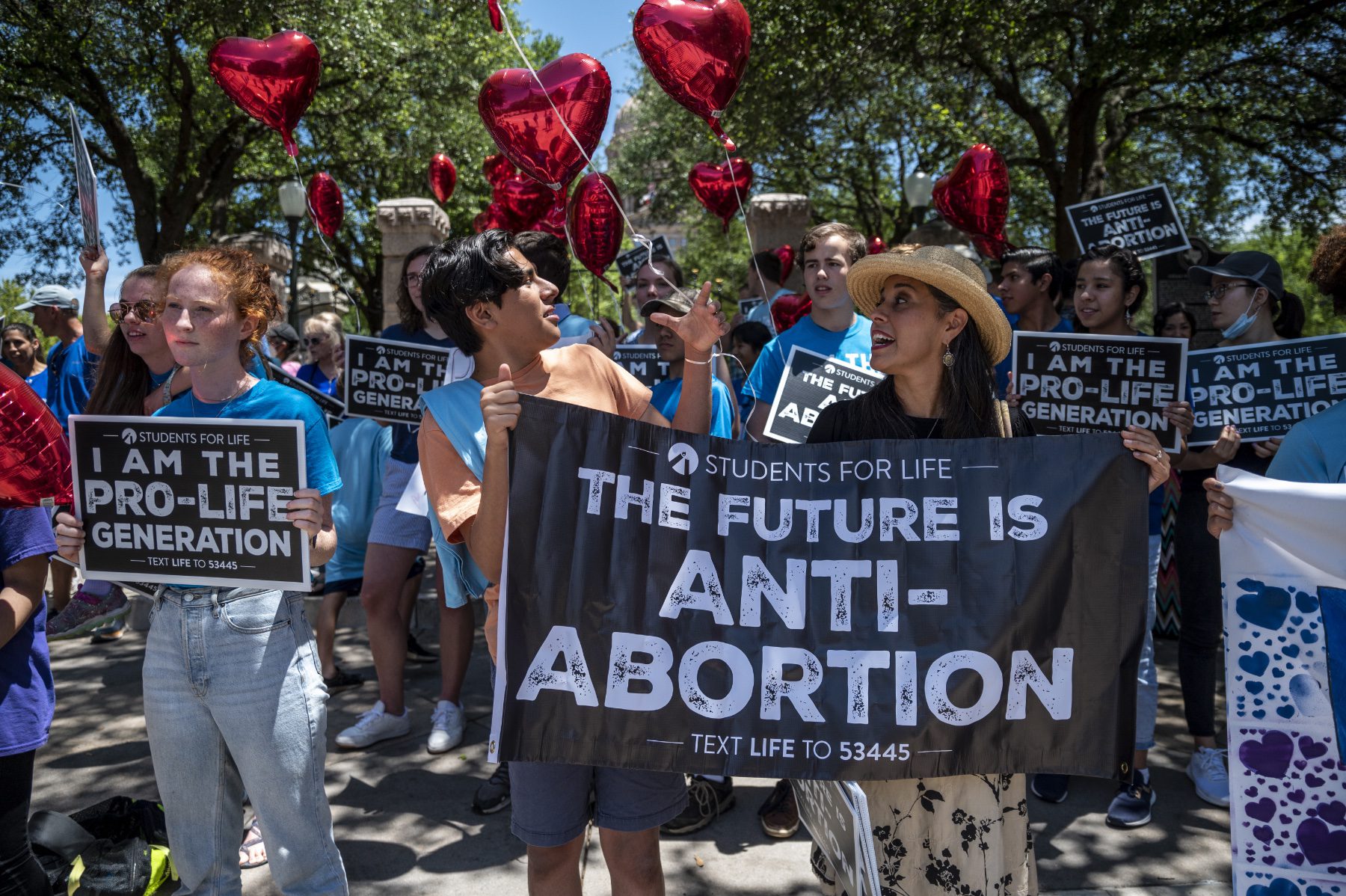 Anti-abortion protesters outside of the Texas Capitol with a sign that reads, 
