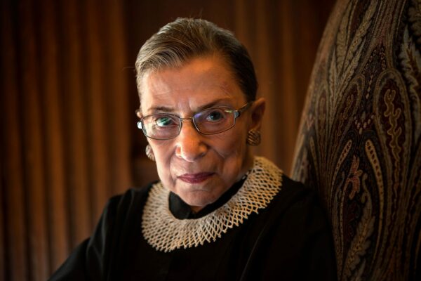 Ruth Bader Ginsburg sits in a chair and looks into the camera.