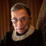 Ruth Bader Ginsburg sits in a chair and looks into the camera.