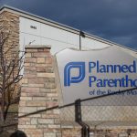 A shadow from a chain link fence falls across the Planned Parenthood of the Rocky Mountains sign.