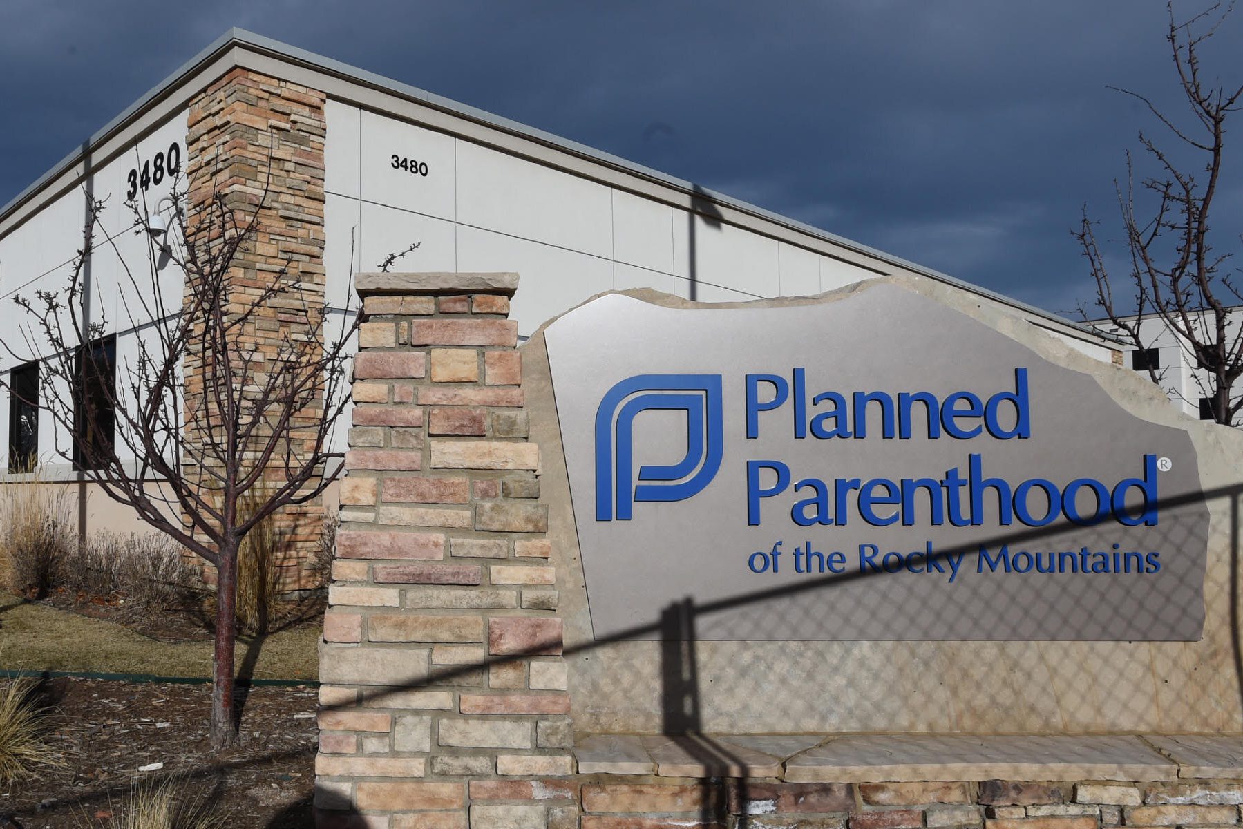 A shadow from a chain link fence falls across the Planned Parenthood of the Rocky Mountains sign.