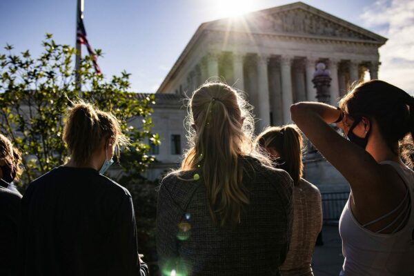 Women wearing masks stand near the U.S. Supreme Court