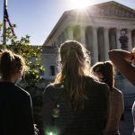Women wearing masks stand near the U.S. Supreme Court