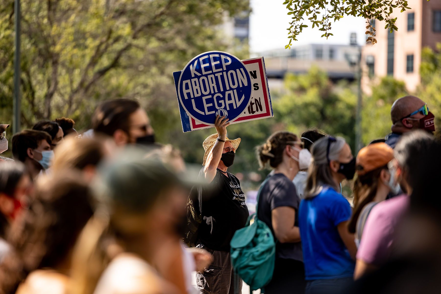 A person wearing a sat holds up a sign that reads "Keep Abortion Legal" as people gather near the State Capitol to protest the new abortion bill.