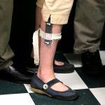 A female student wears a shocking device on her leg.