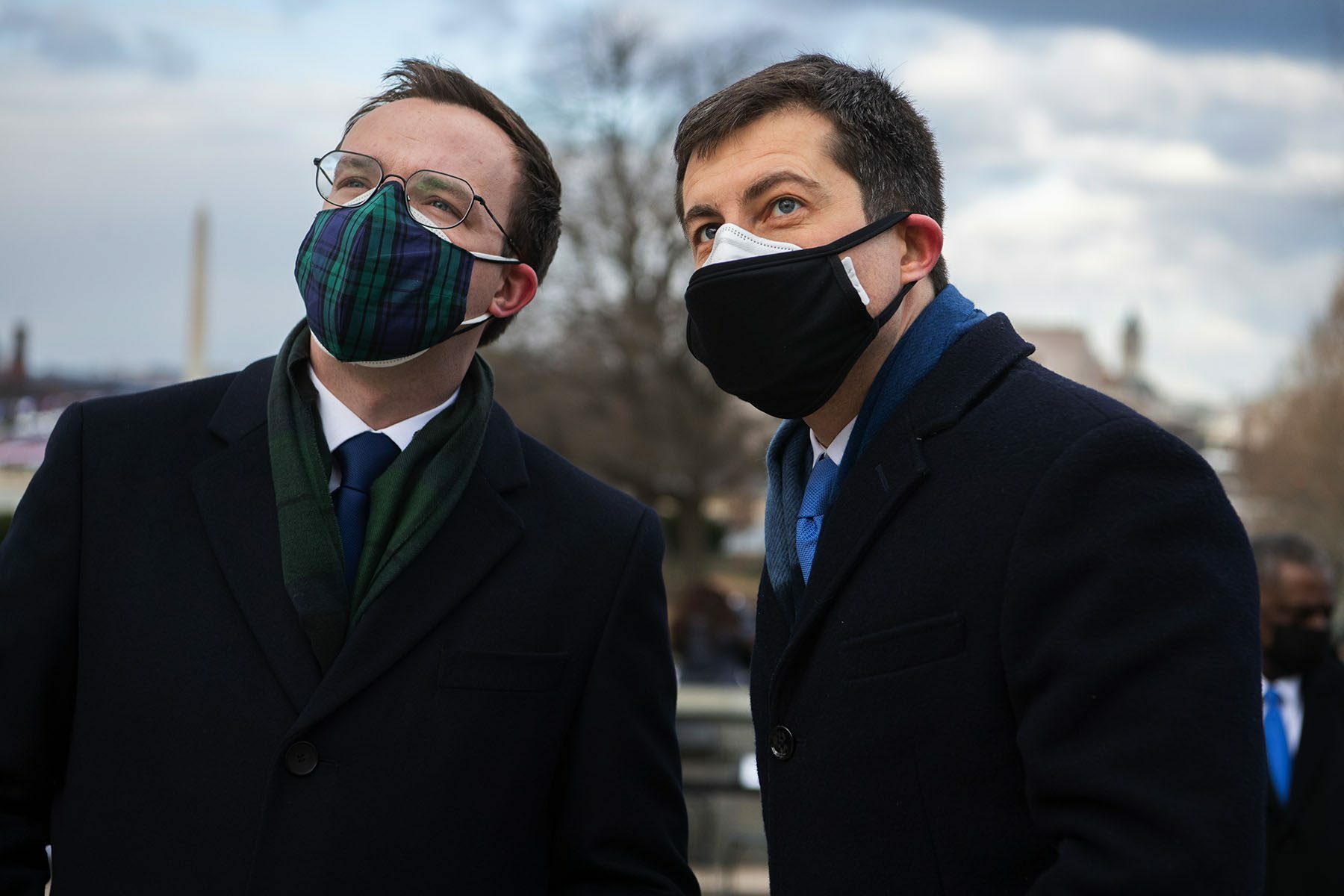 Pete Buttigieg his husband Chasten lean towards each other. They are both wearing face masks.