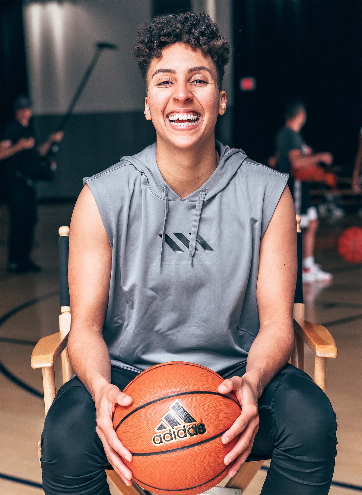 Layshia Clarendon holds a basketball and grins while she poses for a portrait.