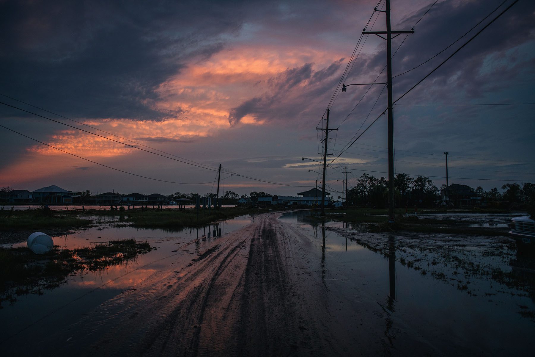 The reflection of a colorful sunset is seen on a flooded road.