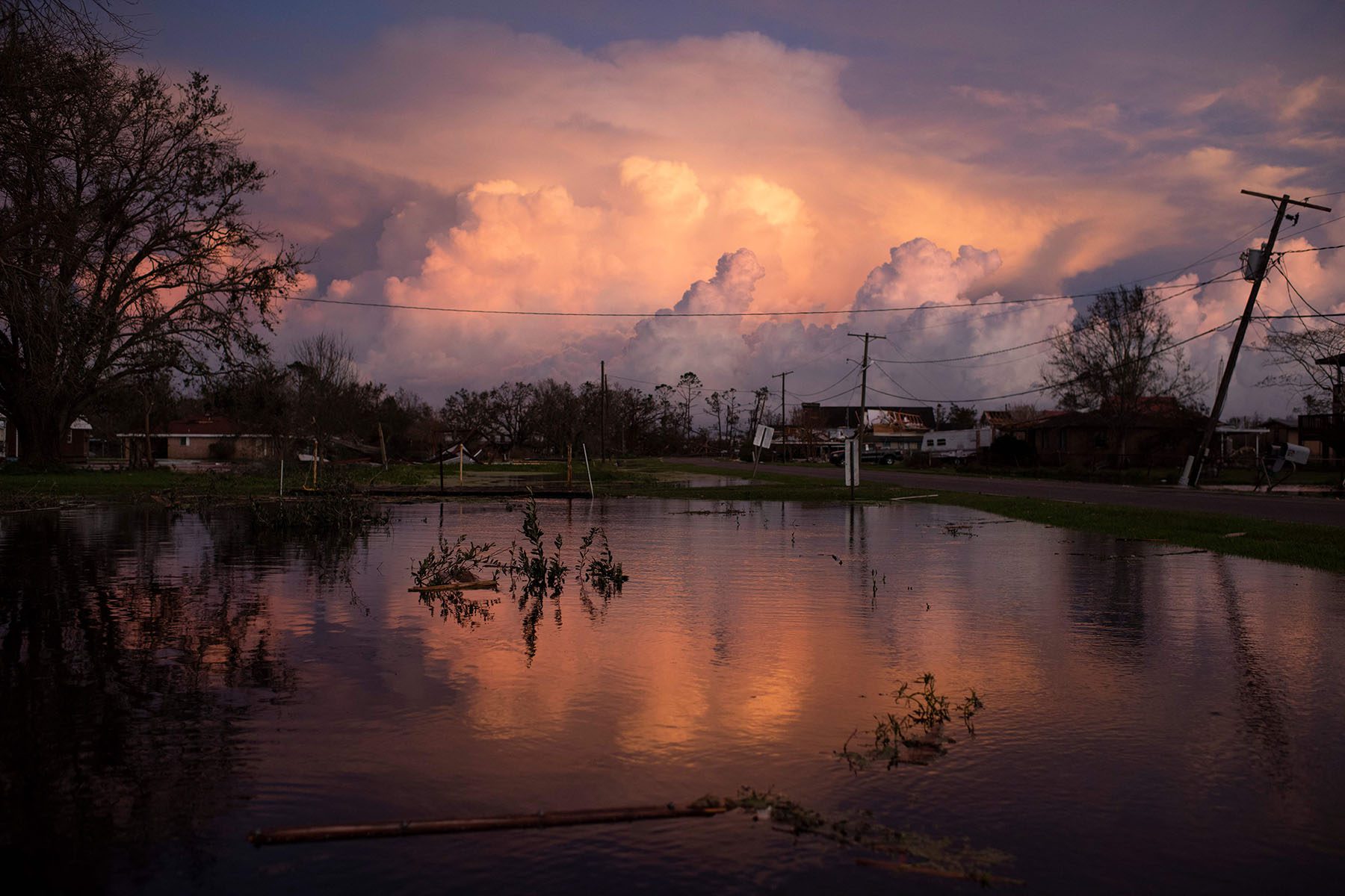 Large storm clouds are seen in the sky as a flooded road reflects the colorful sunset.