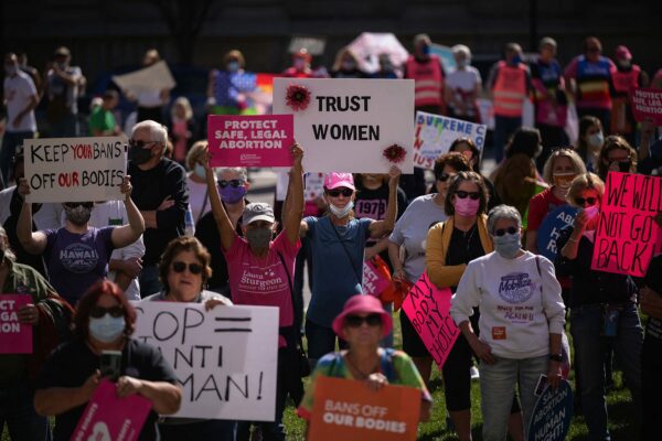 A crowd of abortion rights activists carry signs while demonstrating.