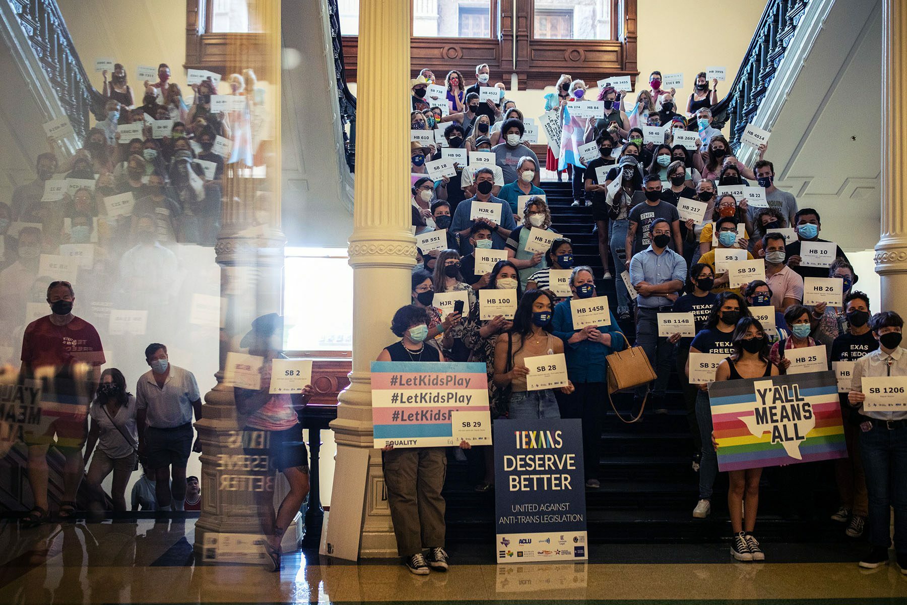LGBTQ+ rights supporters inside the Texas State Capitol. Many hold signs, some read 