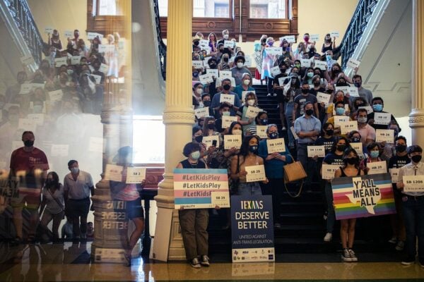 LGBTQ+ rights supporters inside the Texas State Capitol. Many hold signs, some read 