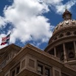 A U.S. and a Texas flag fly over the Texas State Capitol.