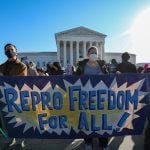 People carry a banner on reproductive freedom in front of the Supreme Court