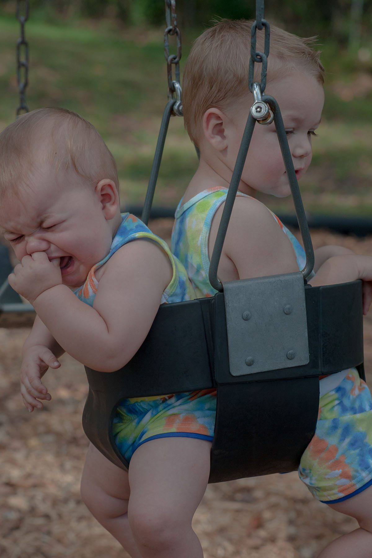 Children play on a swing set, the youngest cries.