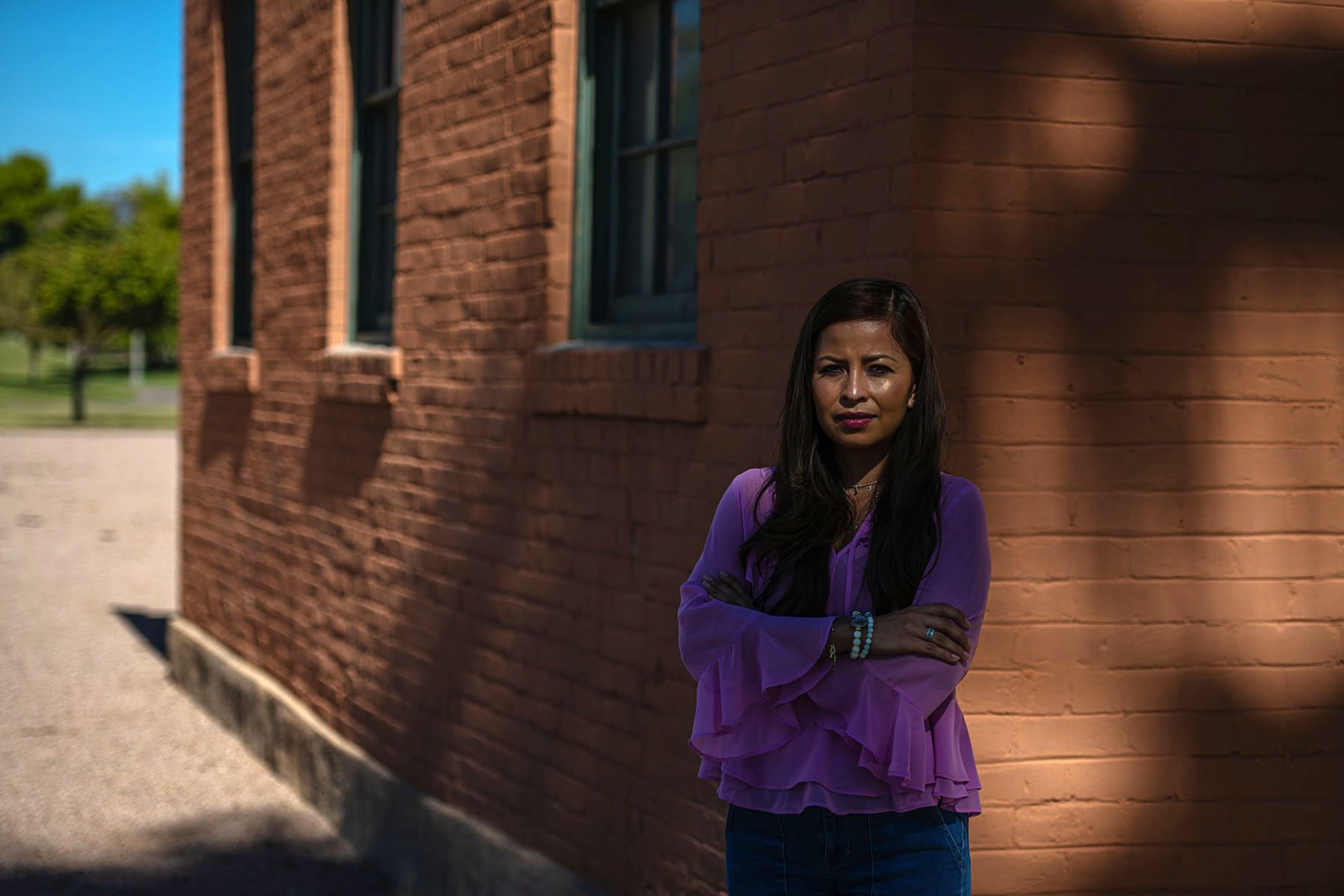 Ylenia Aguilar poses for a portrait near a brick building.