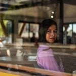 Ylenia Aguilar looks out the window as she poses for a portrait in a cafe