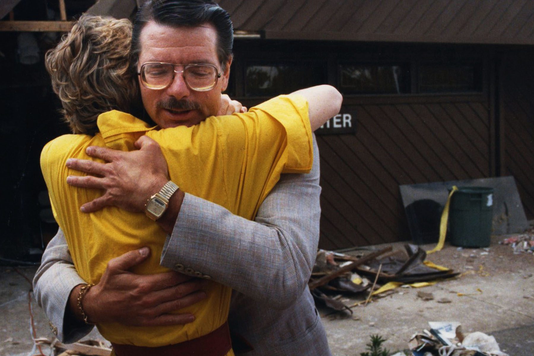 Dr. George Tiller hugs a woman. Behind him are piles of wood and trash from the bombing.