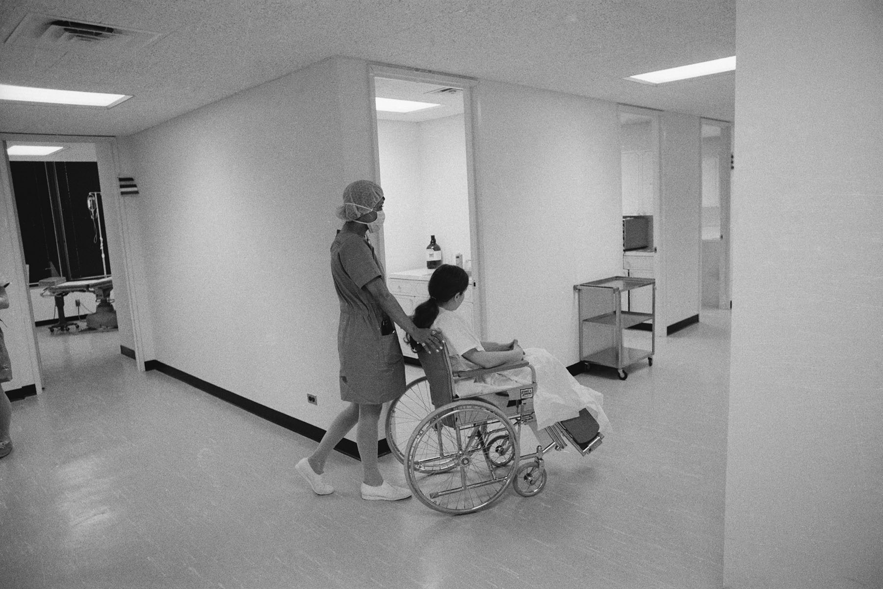 A nurses pushes a patient in a wheelchair.