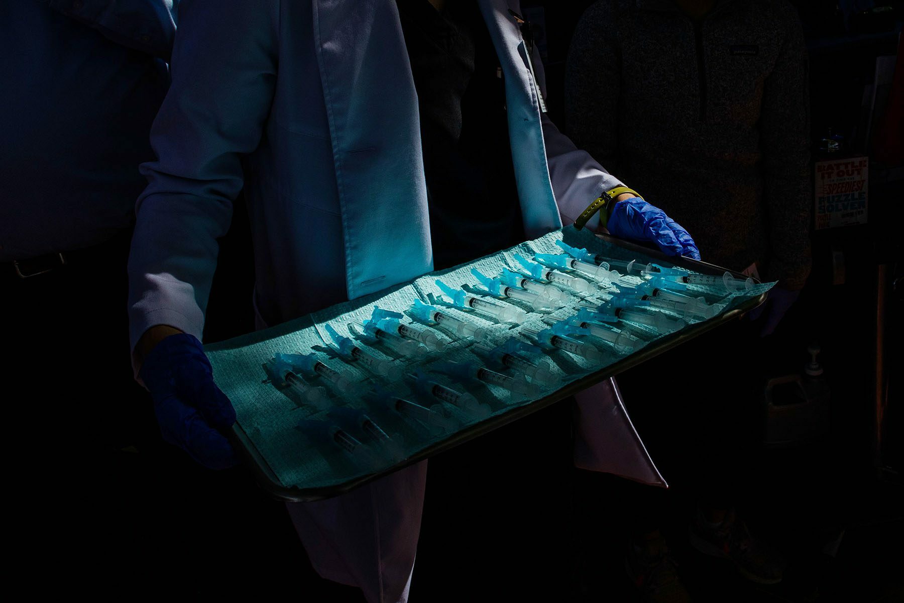 A medical assistant carries a tray of syringes full of COVID-19 vaccination.