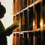 A young girls looks at book in a library.