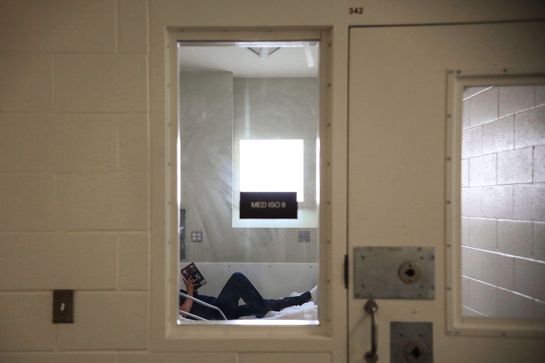 A woman lies down as she reads a book at a prison infirmary.