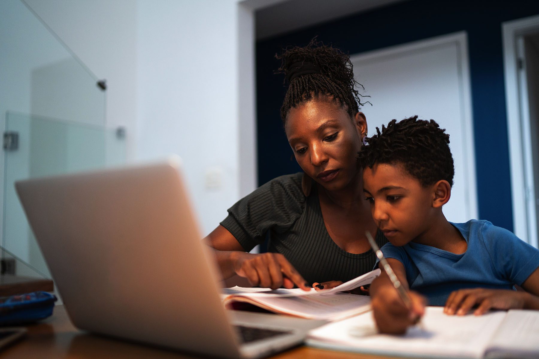 A mom helps her son with homework at home.