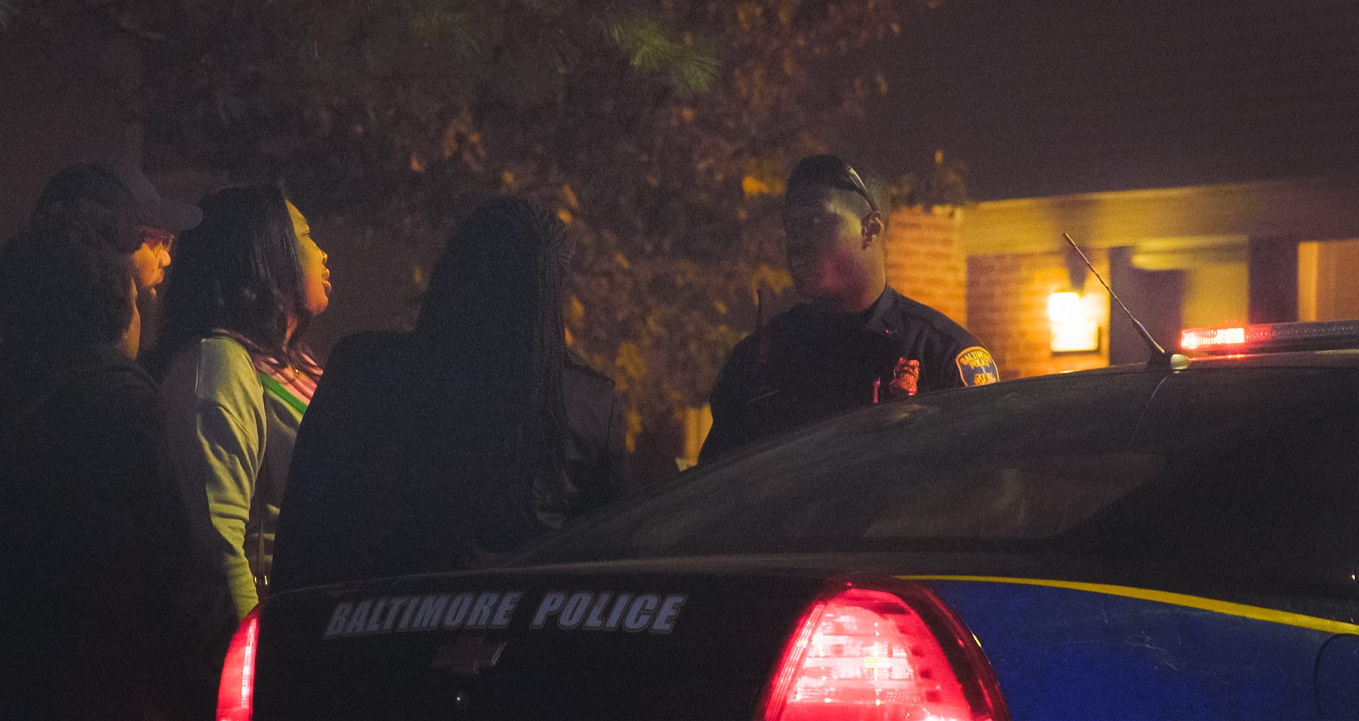 Community members speak to a police officers at night.
