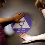 Students place a sticker on the door at the ceremonial opening of a gender neutral bathroom.