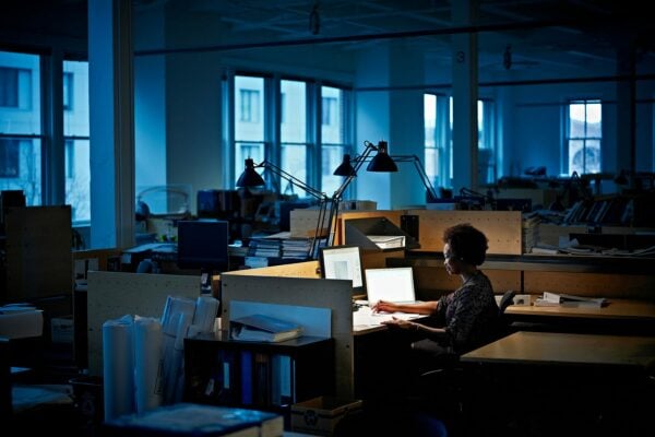 A woman works at her desk in empty office at night.