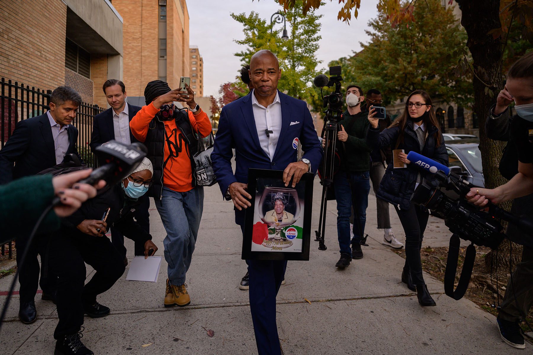 Eric Adams holds a photograph of his late mother as he leaves a voting center.