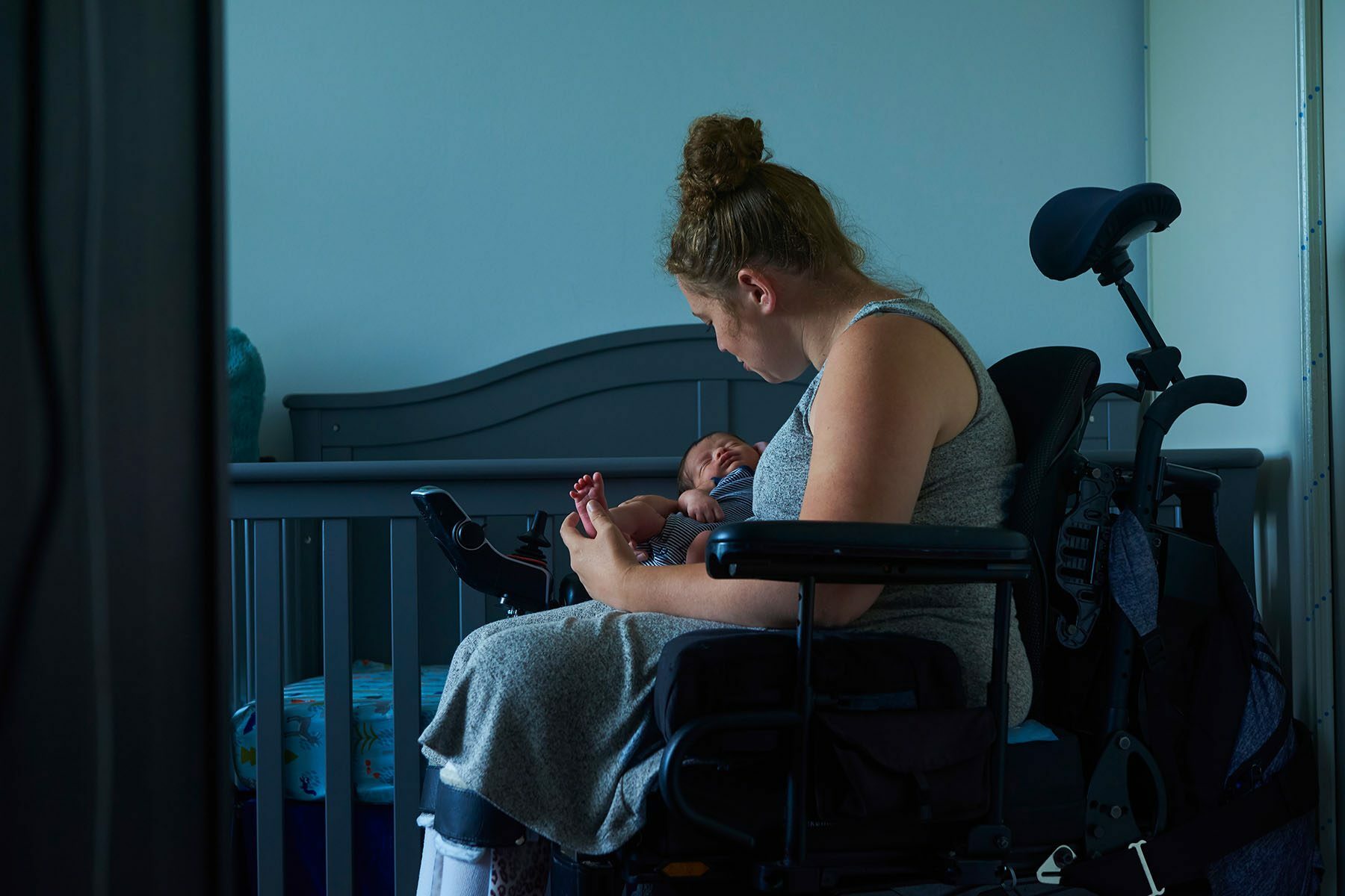 A mother in a wheel chair holds her baby in her arms.