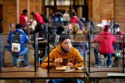 Students eat lunch separated from classmates by plastic dividers.