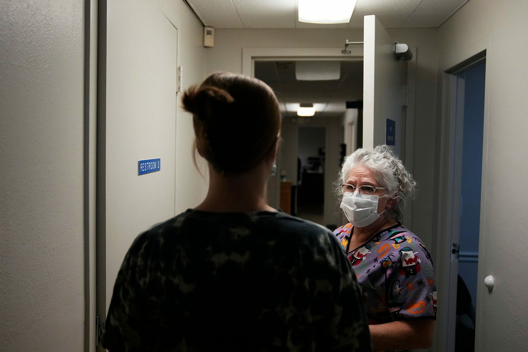 A woman accompanied by a lab technician walks down the hall at an abortion clinic.