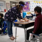 A teacher helps a student during class at an elementary school.