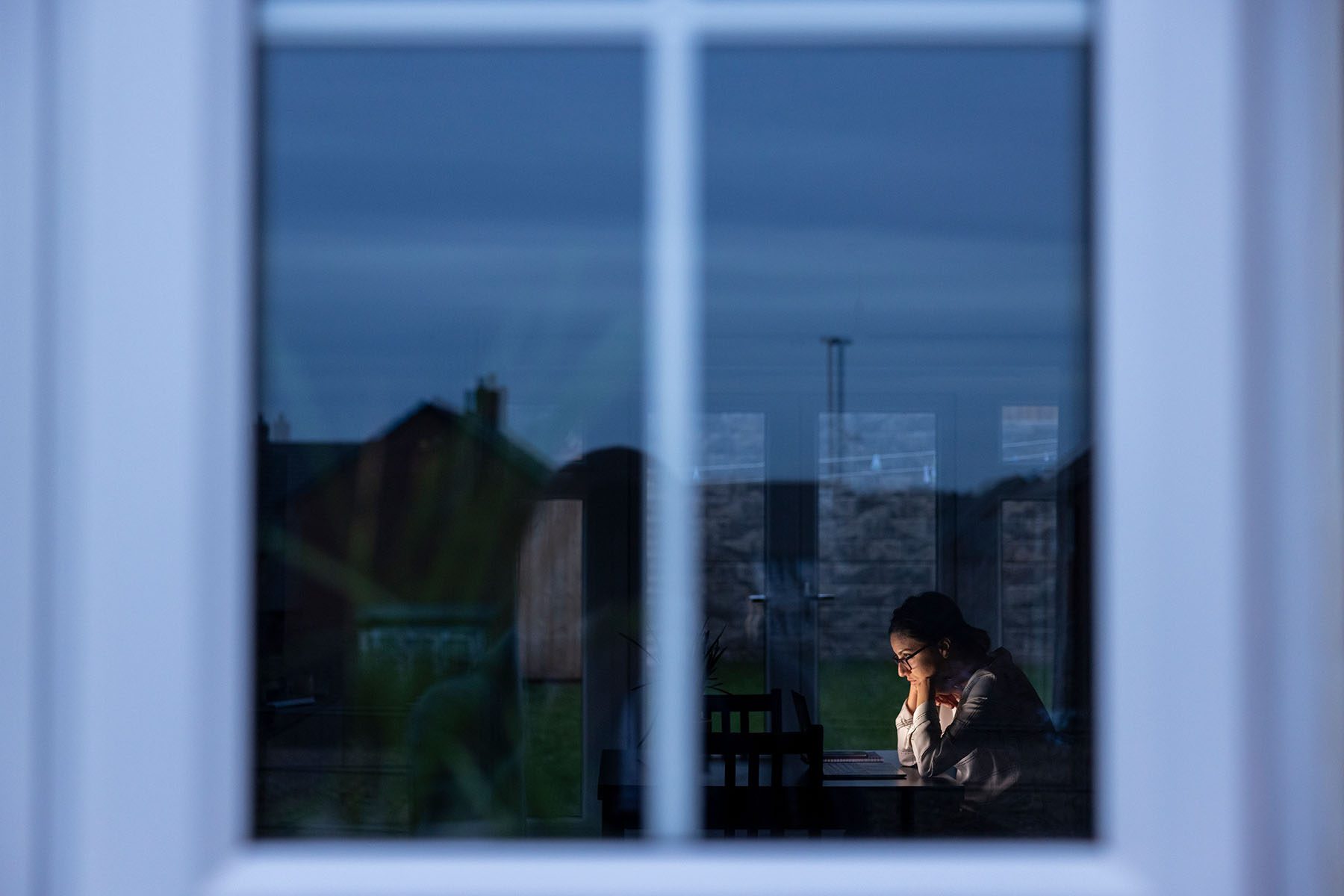 A woman is seen on a computer through a window.