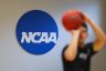 A person prepares to shoot a basketball standing in front of a NCAA logo.