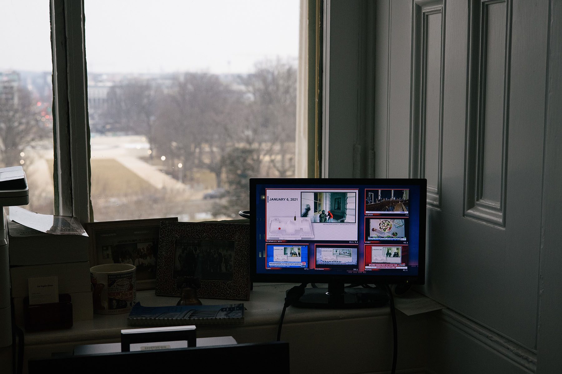 Video of the January 6th attack plays on a small screen in a press gallery.