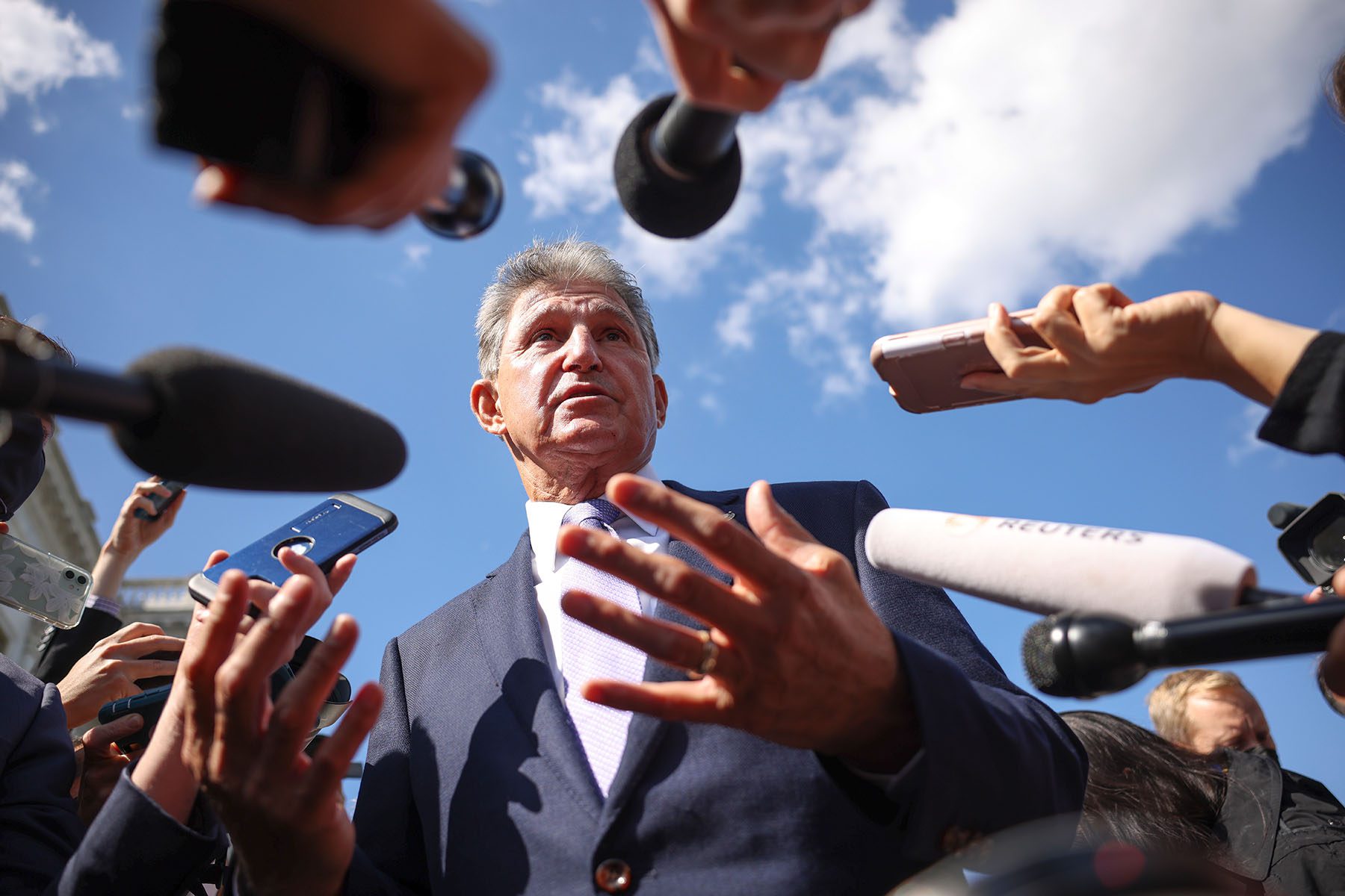 Joe Manchin is surrounded by reporters outside the U.S. Capitol.